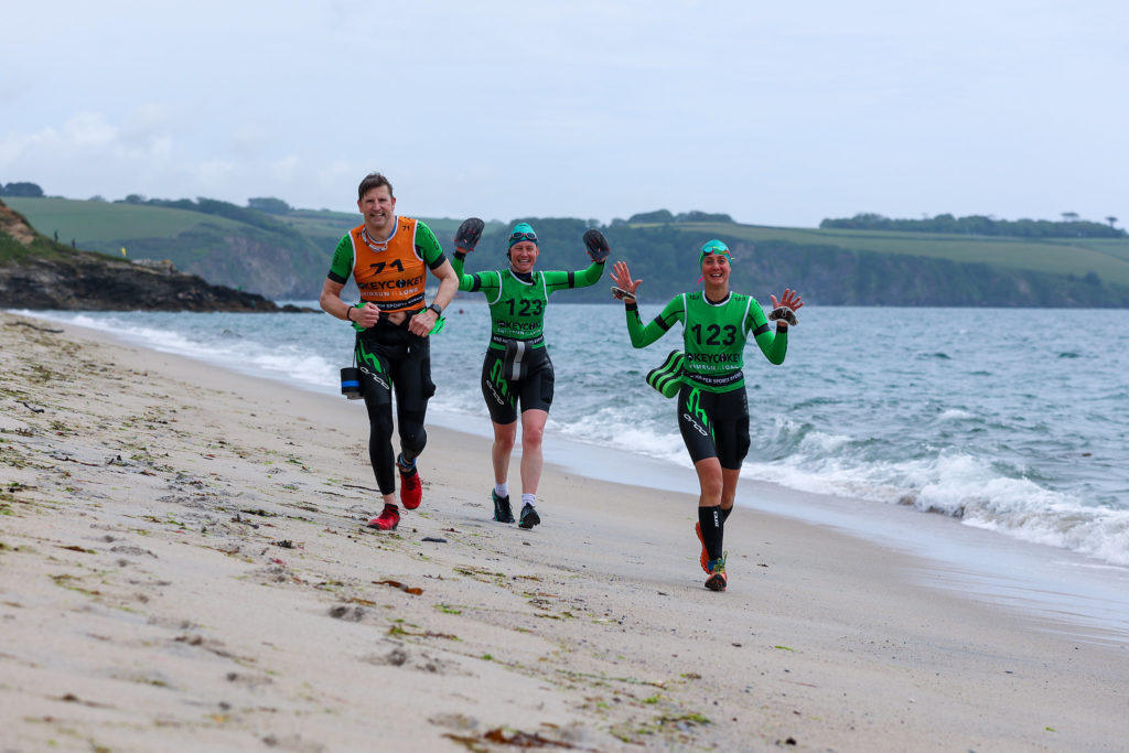 3 competitors in the hokey cokey swimrun running along the beach