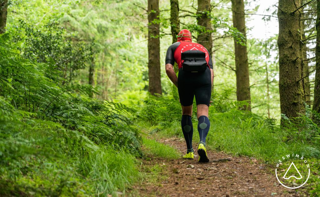 jon littlewood running wearing the x-talons on a technical trail in the forest